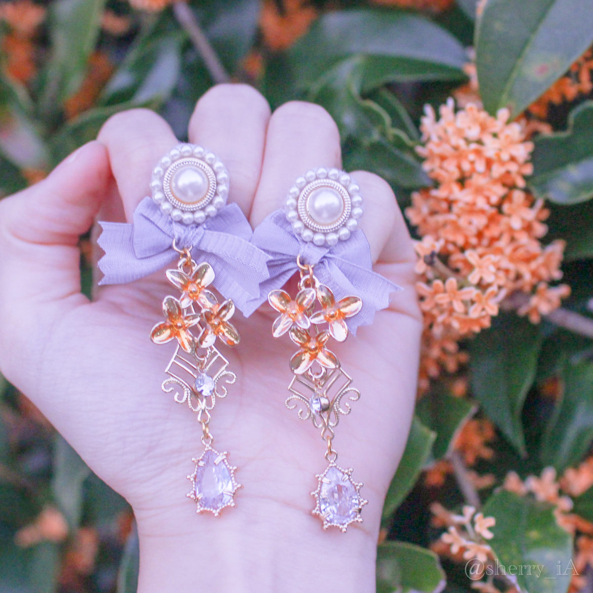 アミュリボン 金木犀のクリスタルガーデン 耳飾り オレンジに着色したレジンで作った金木犀のチャームと煌めくビジューで作った金木犀のハンドメイドアクセサリー 金木犀とともに撮ったピアス/イヤリング 藤色