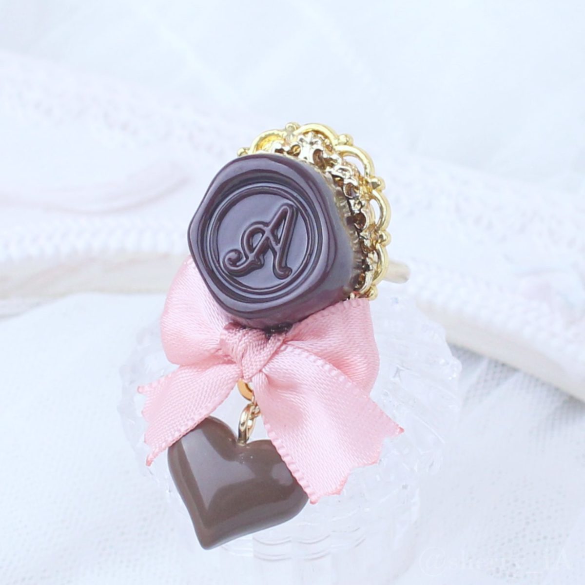 アミュリボン ロマンスチョコリング シーリングスタンプモチーフのチョコレートにリボンとチョコで作ったハンドメイドアクセサリー ピンク
