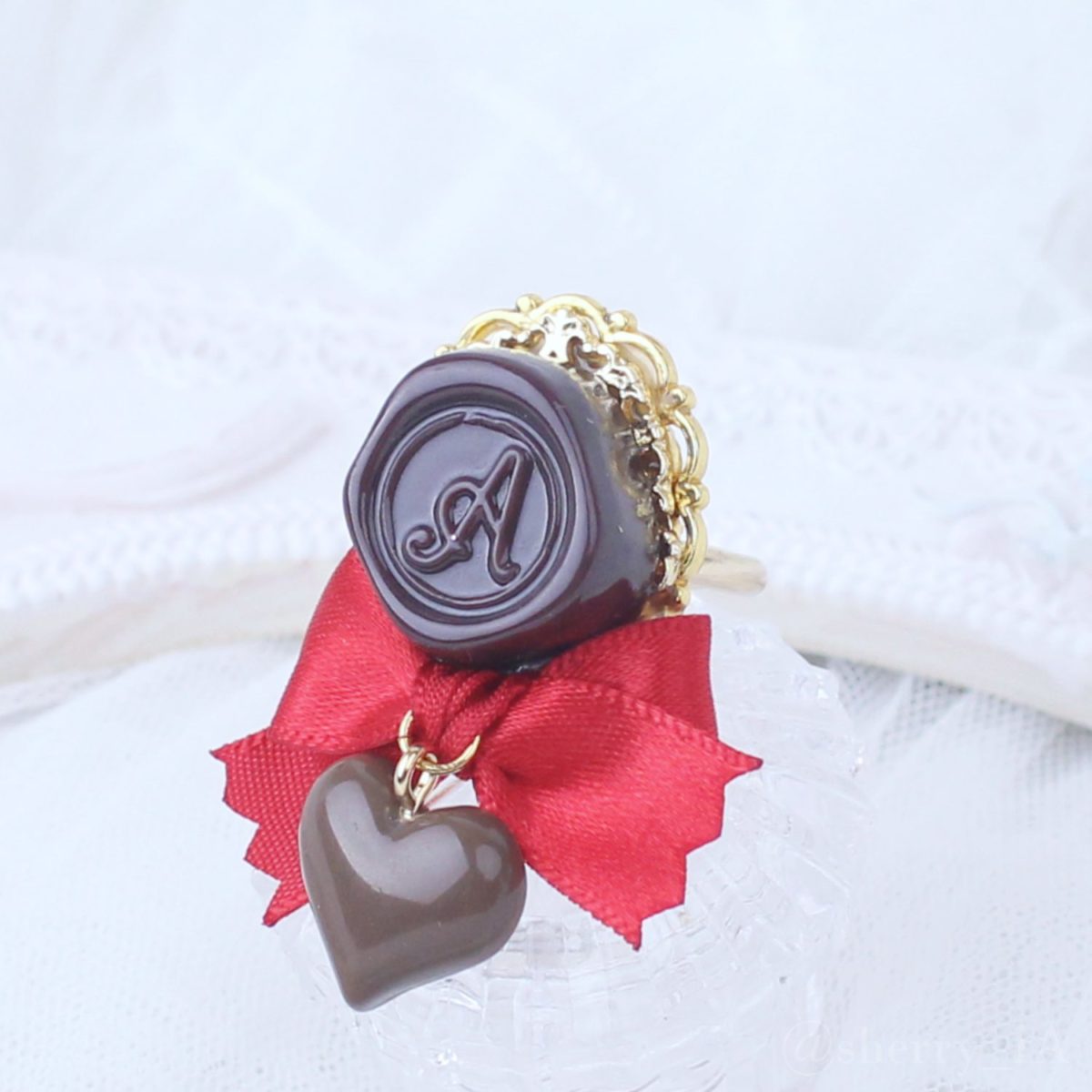 アミュリボン ロマンスチョコリング シーリングスタンプモチーフのチョコレートにリボンとチョコで作ったハンドメイドアクセサリー 赤色